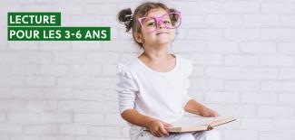 enfant à lunettes tenant un livre dans ses mains
